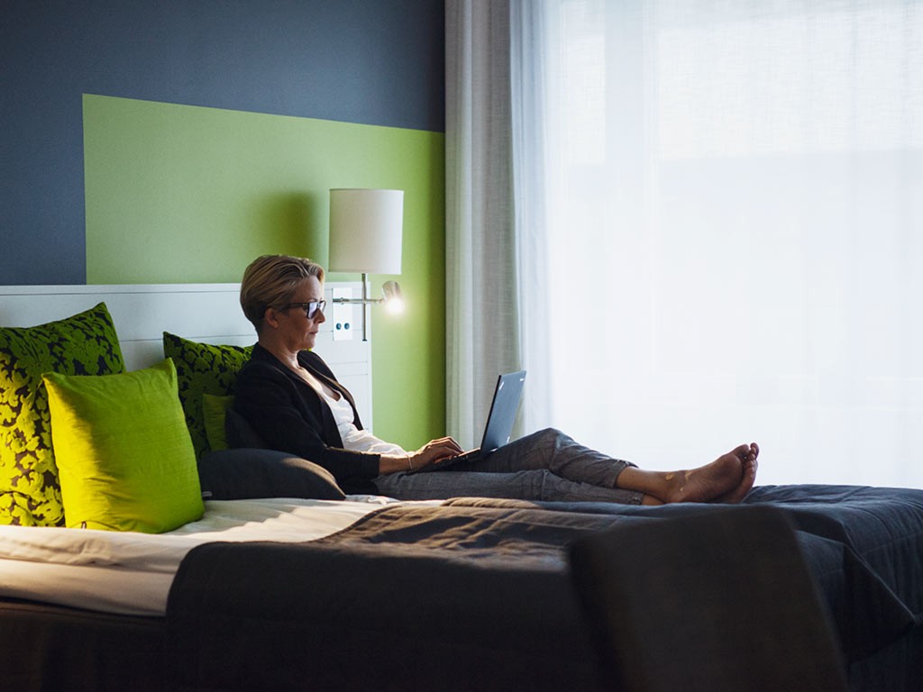 Kvinna sitter framför laptop Sky Hotel Apartments Stockholm